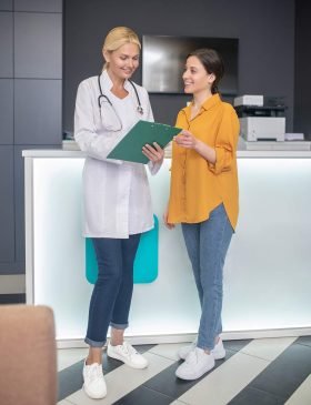 blond-doctor-helping-in-white-robe-standing-in-hal-2024-10-18-04-30-17-NW675S8.jpg